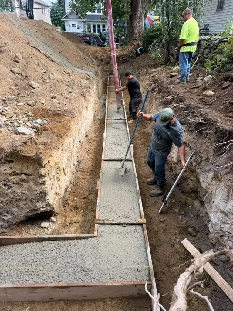 A crew placing and screeding concrete in footing forms