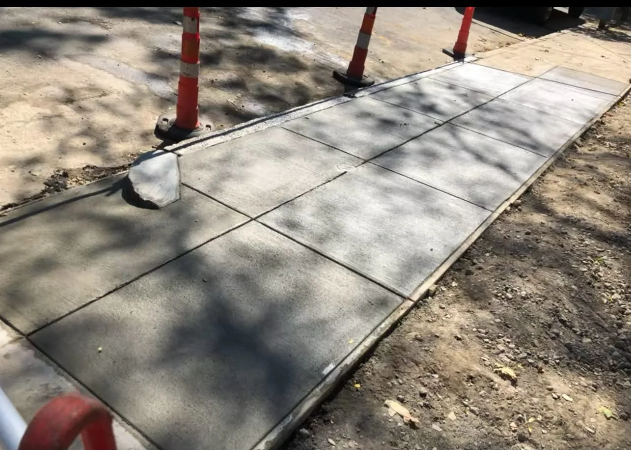 A new broom-finished concrete sidewalk with control joints
