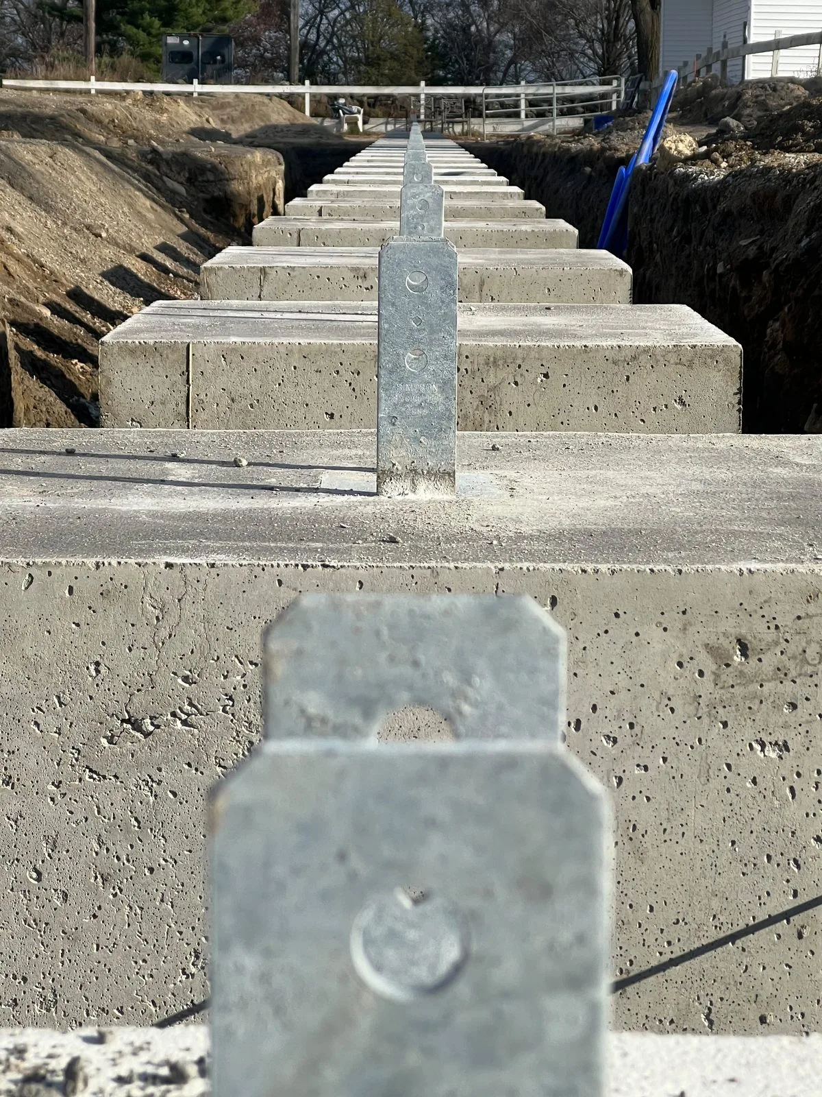 A row of concrete pier footings with steel post brackets
